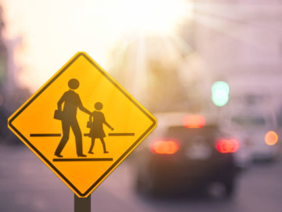 School zone warning sign on blur traffic road with colorful bokeh light abstract background. Copy space of transportation and travel concept. Vintage tone color style.